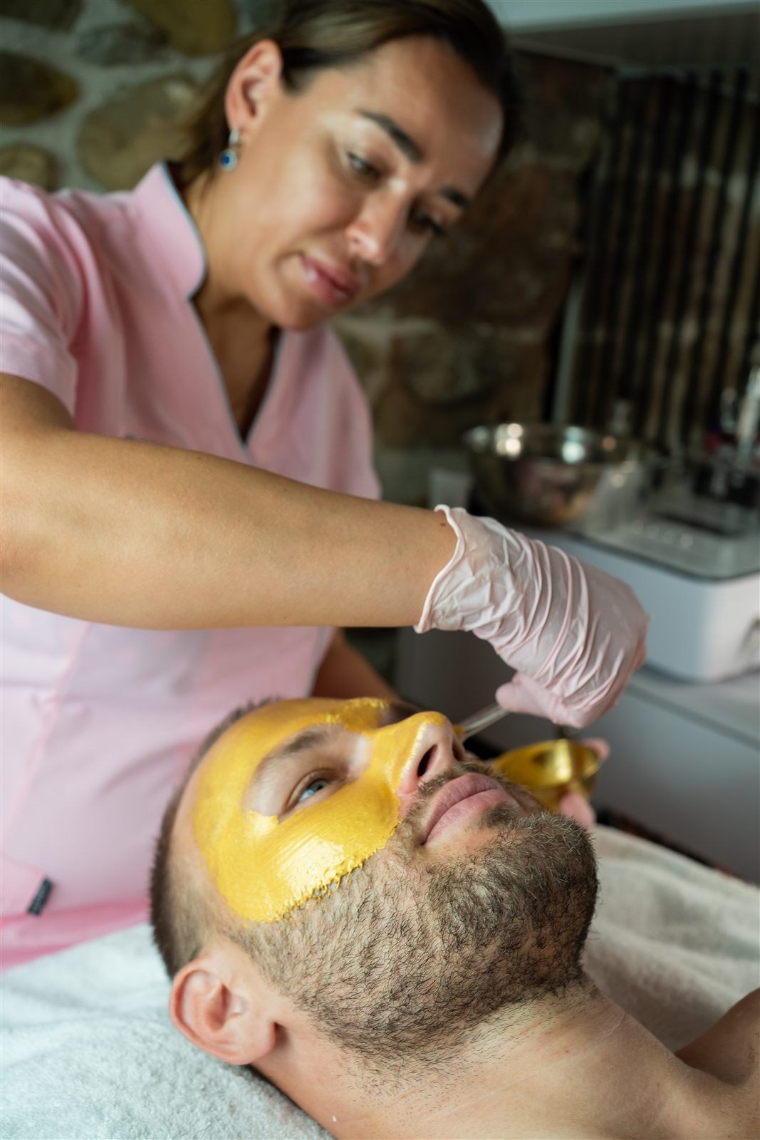 Therapist applying a facial mask to a male client